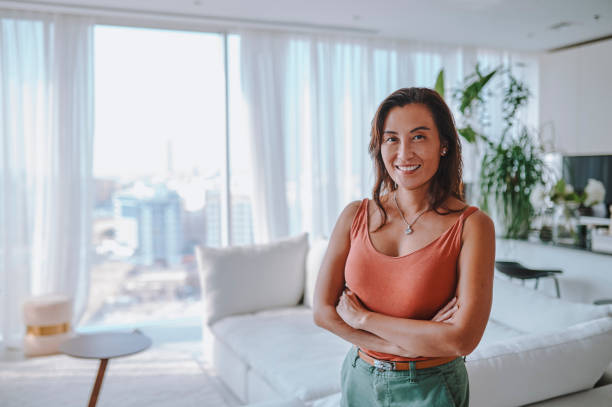 A woman stands confidently in a bright, modern apartment, embodying success in saving for property in Dubai.